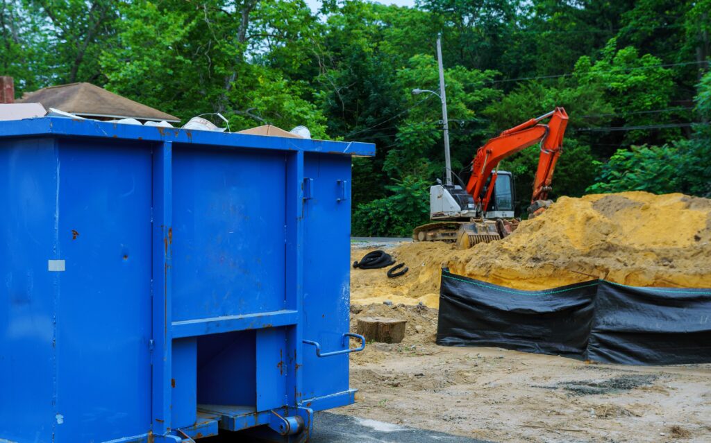 Blue metal waste container with building debris a building for recycling.